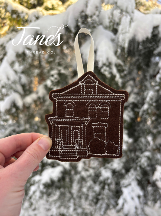 Felt house ornament held in front of a snow-covered tree, with 'Jane's Thread Co.' branding.