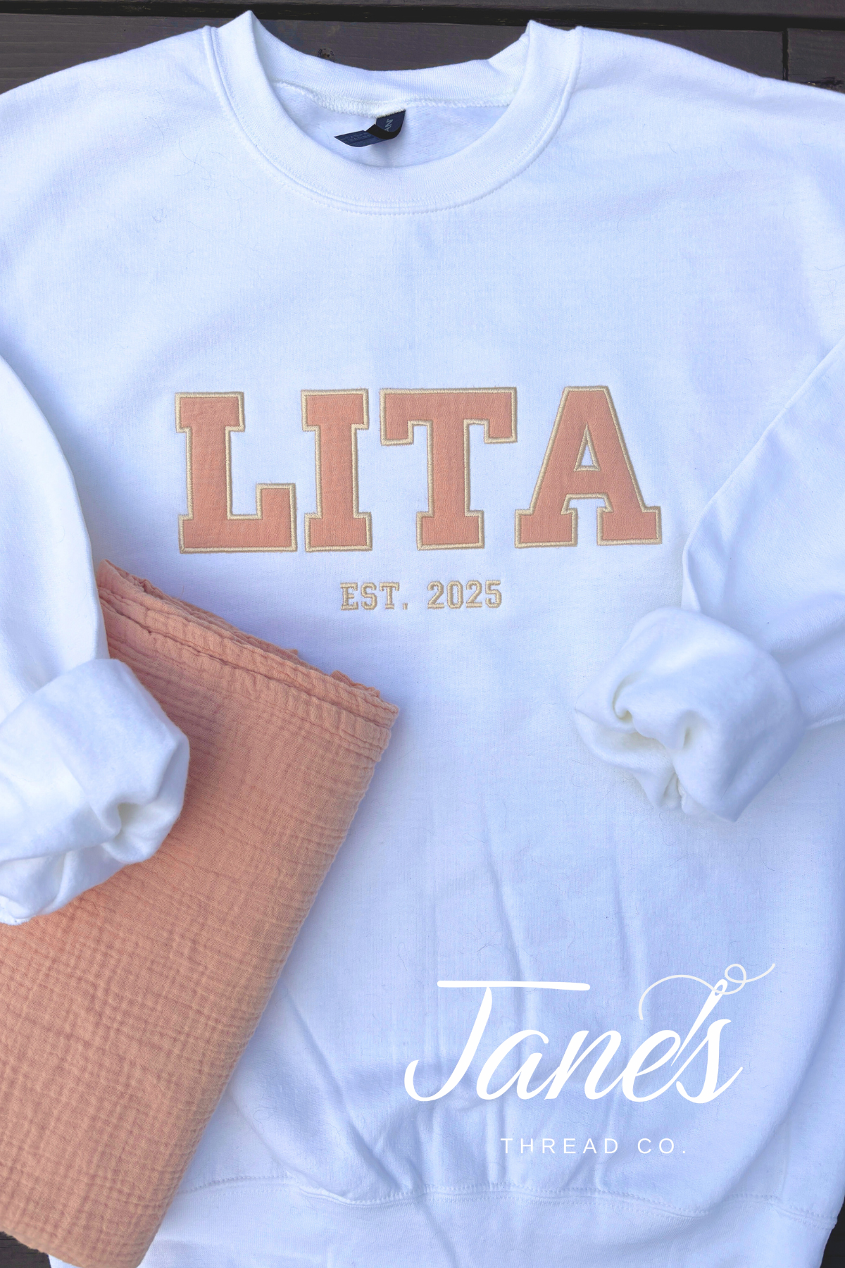 White sweatshirt with 'LITA EST. 2025' text and a brown bag on a white background