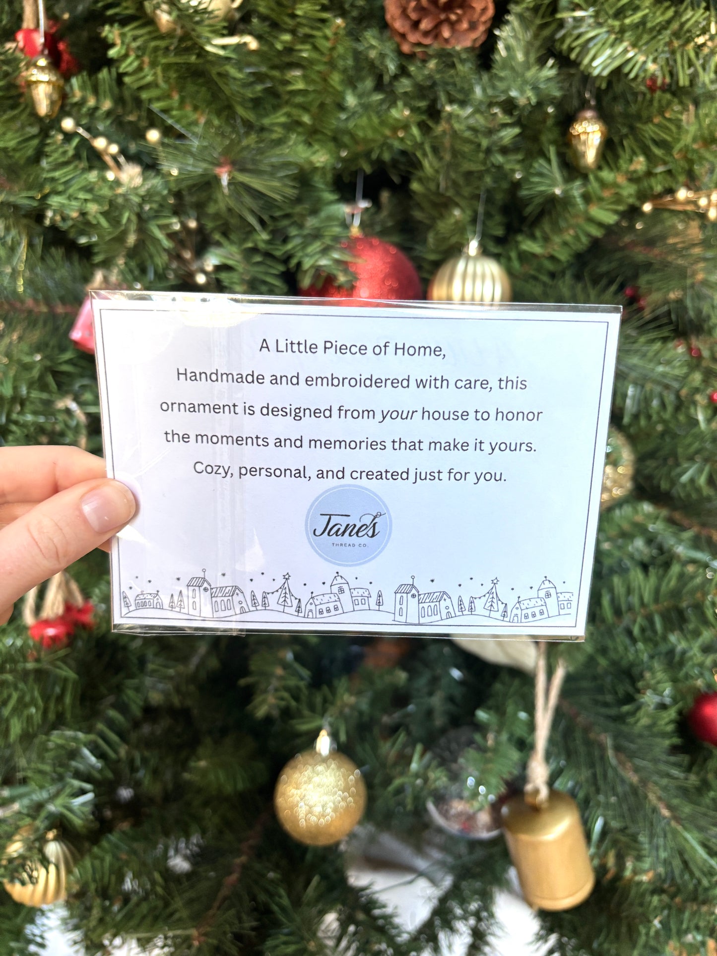 Handheld card with text in front of a decorated Christmas tree