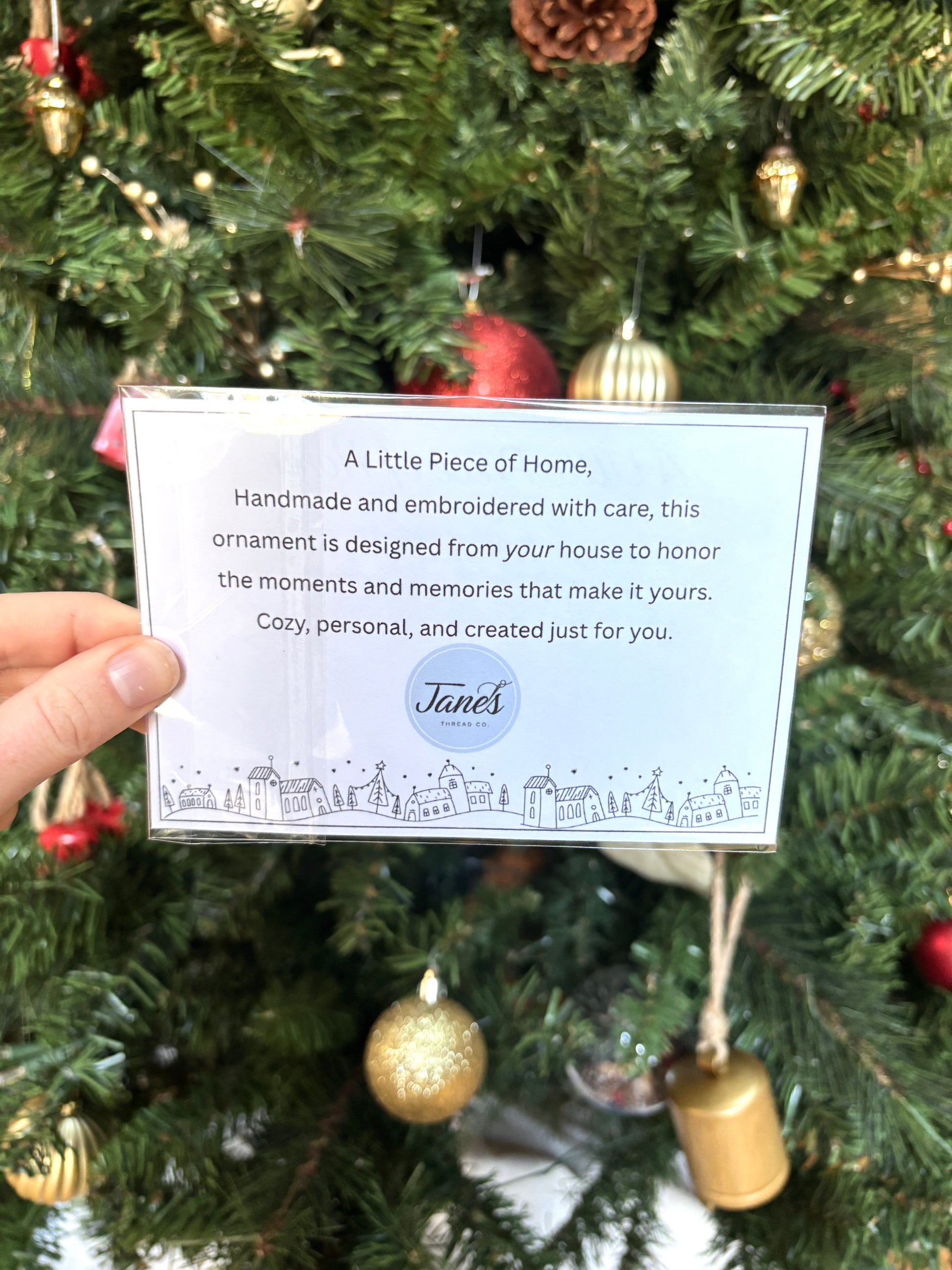 Handheld card with text in front of a decorated Christmas tree