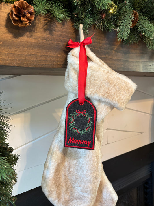 Decorative dog toy with a red ribbon and 'Mommy' tag next to a Christmas tree.