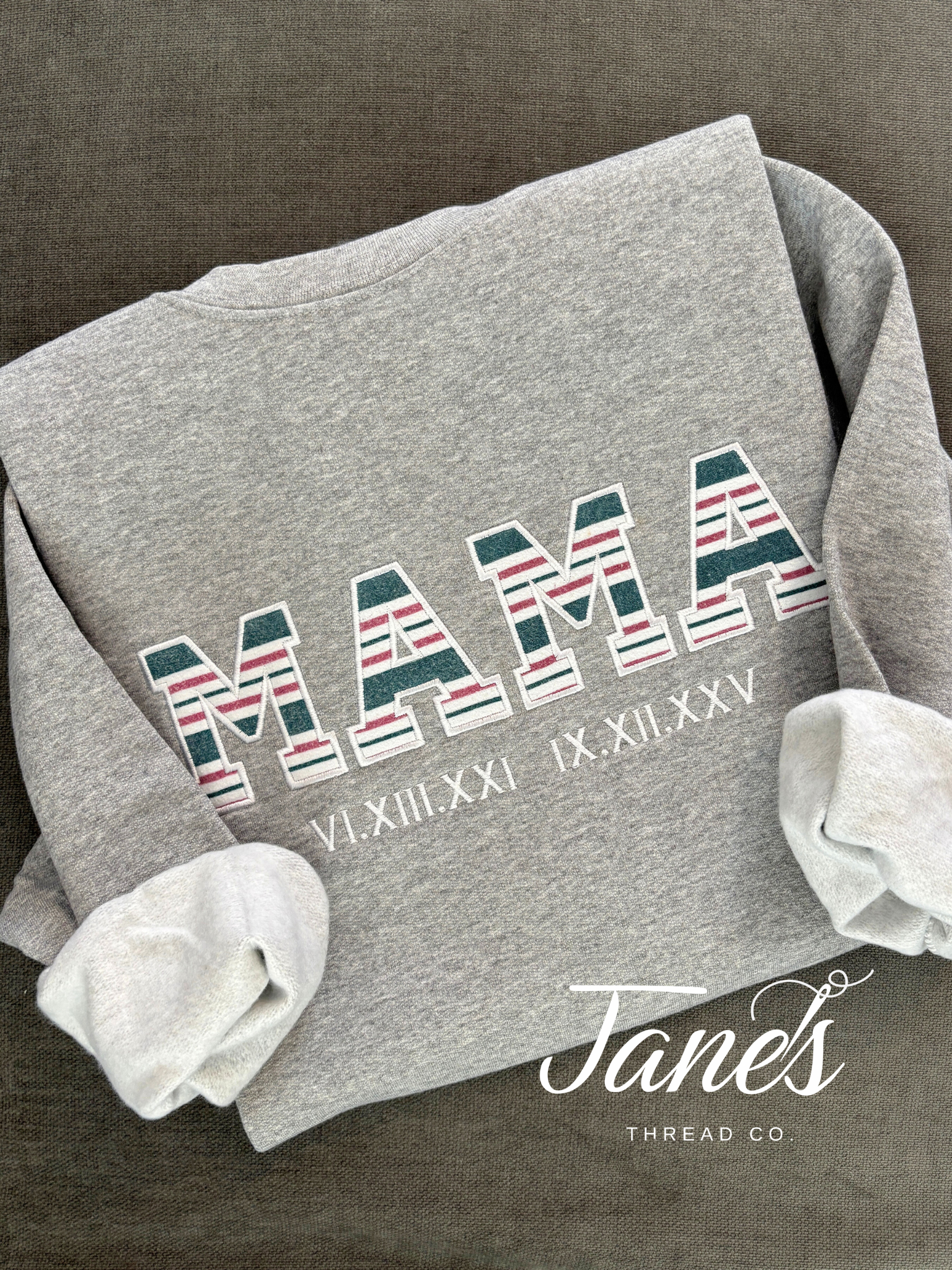 Gray sweatshirt with 'MAMA' and decorative text on a dark background, featuring the brand 'Jane's Thread Co'.