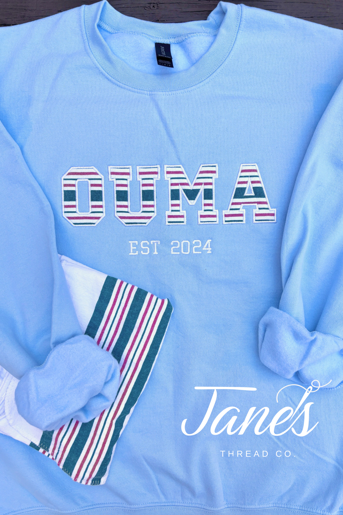 Blue sweatshirt saying "OUMA Est 2024" with baby hospital blanket applique